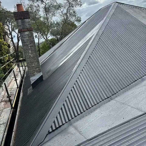 Grey corrugated metal roof built around a brick chimney